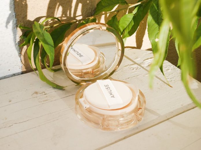 best korean dramas to watch when bored - Amuse makeup cushion displayed with green leaves and natural light on a wooden surface.