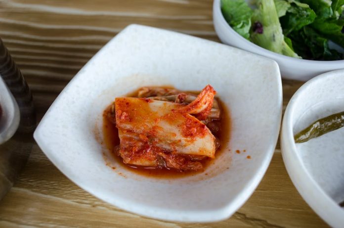gochujang pasta korea recipe trend - Close-up of a delicious Korean kimchi dish served in a white bowl with vibrant spices.