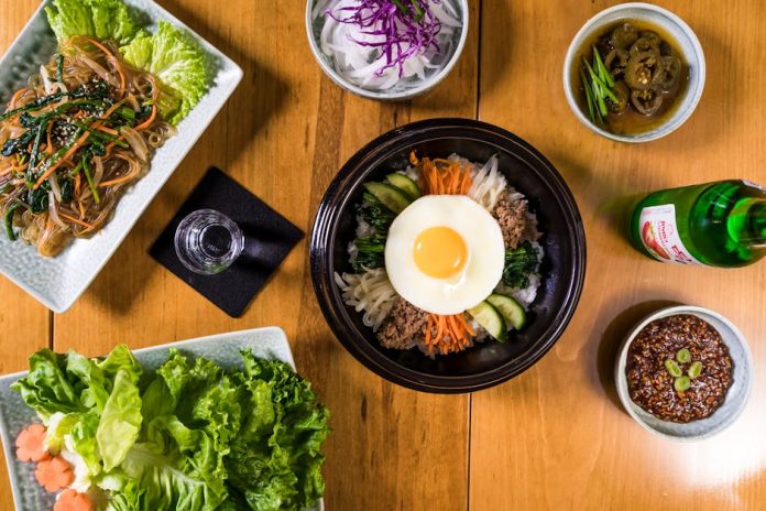 Korean meal kit customization DIY health trend - Delicious assortment of Korean dishes including bibimbap in a flatlay composition.